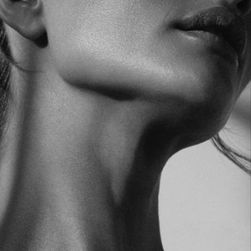 Close-up of a woman's jawline and neck in black and white.