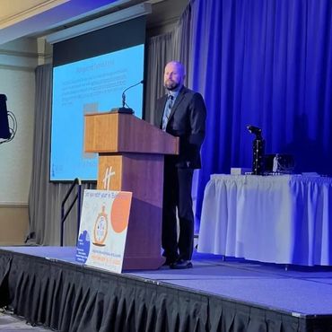 A man in a suit giving a presentation on stage at a conference.