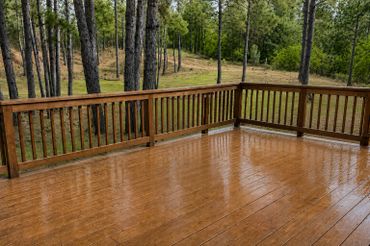 Wet wooden deck surrounded by trees on a rainy day.