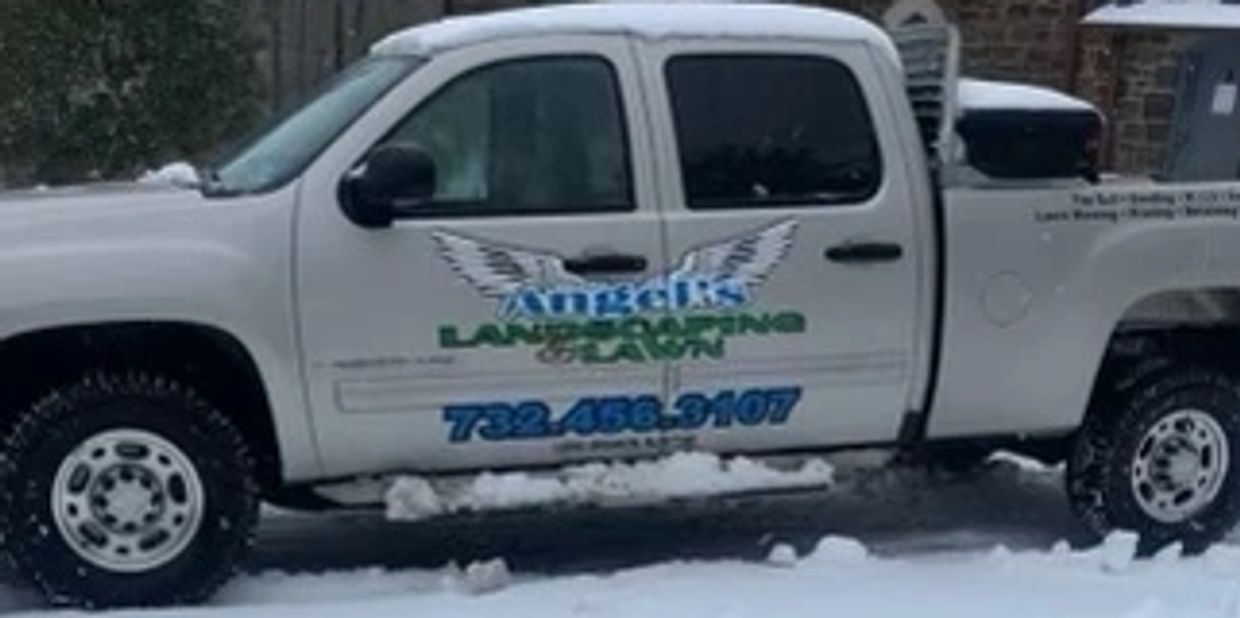 snow covered truck with angels and family landscaping logo on it