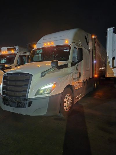 White semi-truck parked at night with lights on.