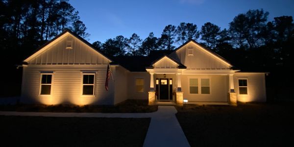 A large white home with windows on the front. garden spotlights. best landscape lights. 