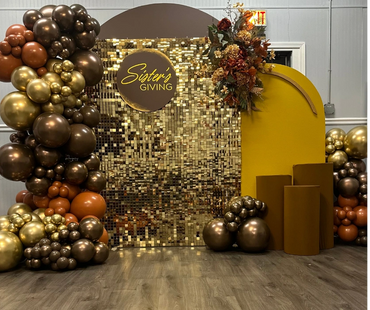 Elegant event setup with gold and brown balloons and a 'Sister's Giving' sign.