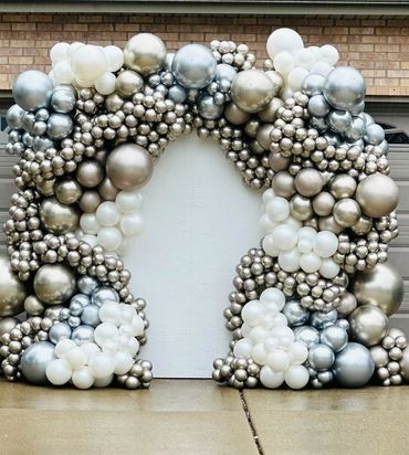 Metallic and white balloon arch in front of a garage door.