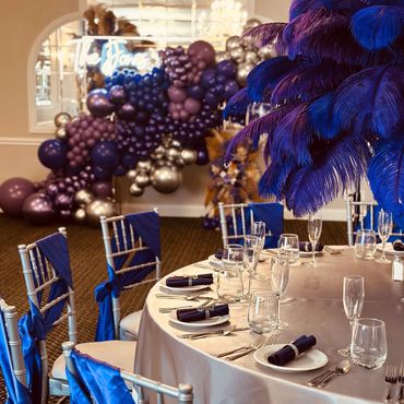 Elegant event table setup with blue feathers and balloons.