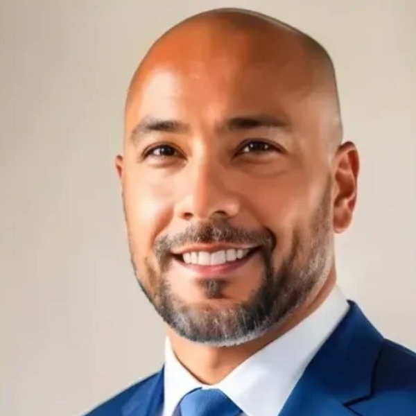A man in a suit and tie smiling for the camera.