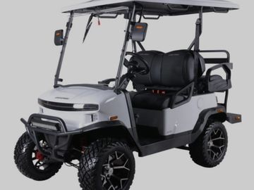 Modern white golf cart with rugged tires and black roof.