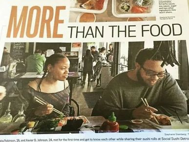 Two people enjoying sushi at Social Sushi Detroit, engaging in conversation and laughter.