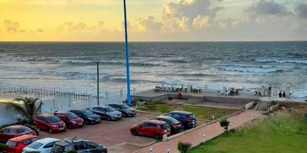 Oceanfront view with a parking lot and swimming pool during sunset.