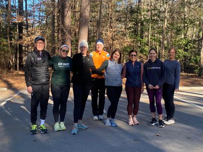 Group of eight people posing outdoors in athletic wear on a sunny day.