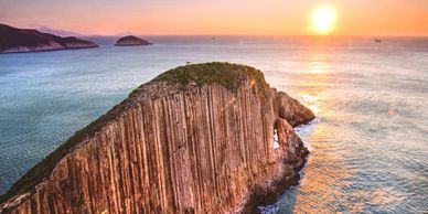 Sunset over a rocky cliff surrounded by ocean waters.