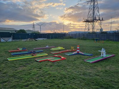 Mini golf course set outdoors during sunset with colorful obstacles.