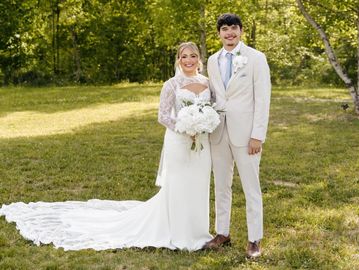 Bride and groom posing outdoors in wedding attire.