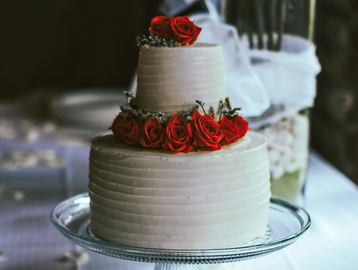 Two-tier white cake decorated with red roses.