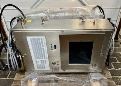 Industrial metal control panel with screen and cables on a pallet.