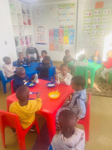 Children eating at colorful tables in a bright classroom.