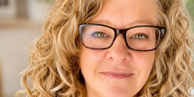 Close-up of a woman with curly hair and glasses.