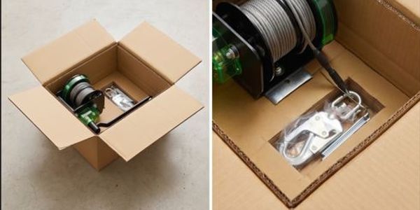 A winch and accessories packaged inside an open cardboard box.
