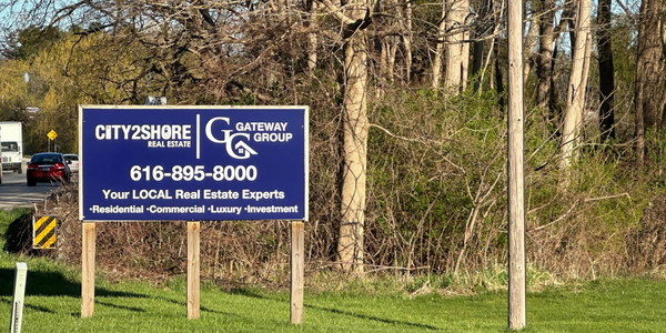 City2Shore Gateway Group real estate sign by roadside with trees in background.