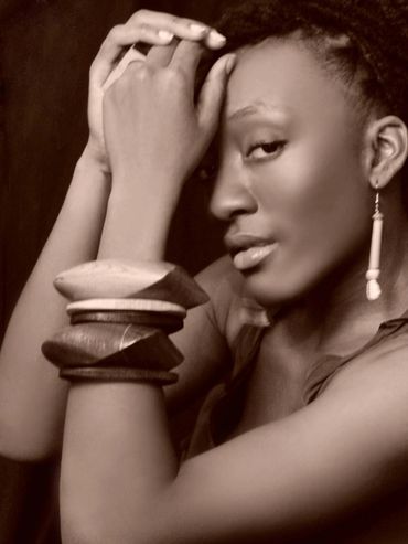 Artistic sepia portrait of a woman with unique wooden bracelets and an earring.