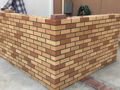 Corner view of a neatly constructed brick wall with patterned bricks.