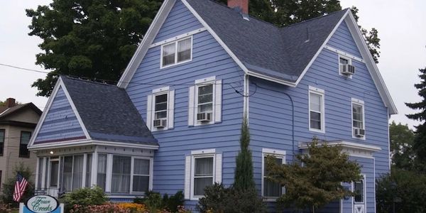 Blue bed and breakfast house with white trim and lush garden.