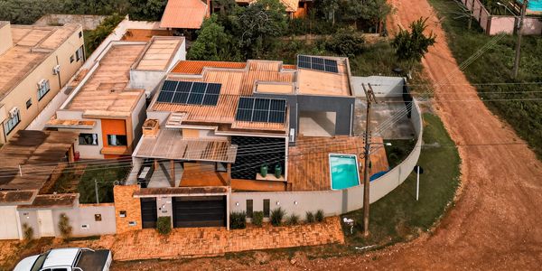 Modern house with solar panels and a small pool, surrounded by a curved wall.
