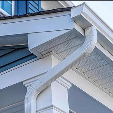 White gutter downspout attached to a house corner.