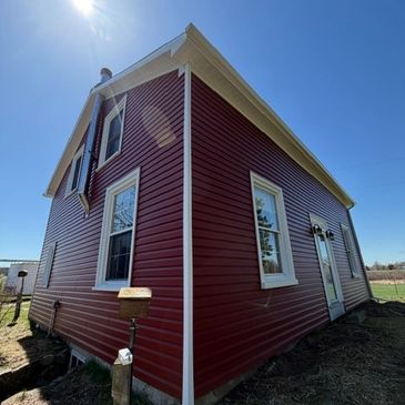 Red house with white trim under a bright blue sky.
