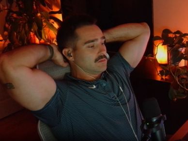 Man relaxing in a dimly lit room with headphones and a microphone.