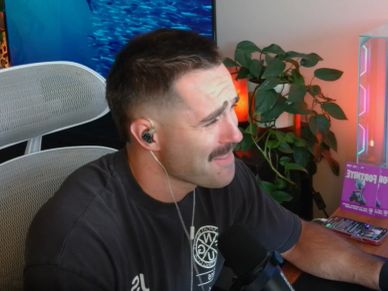 Man with headphones sitting at a desk with a microphone.