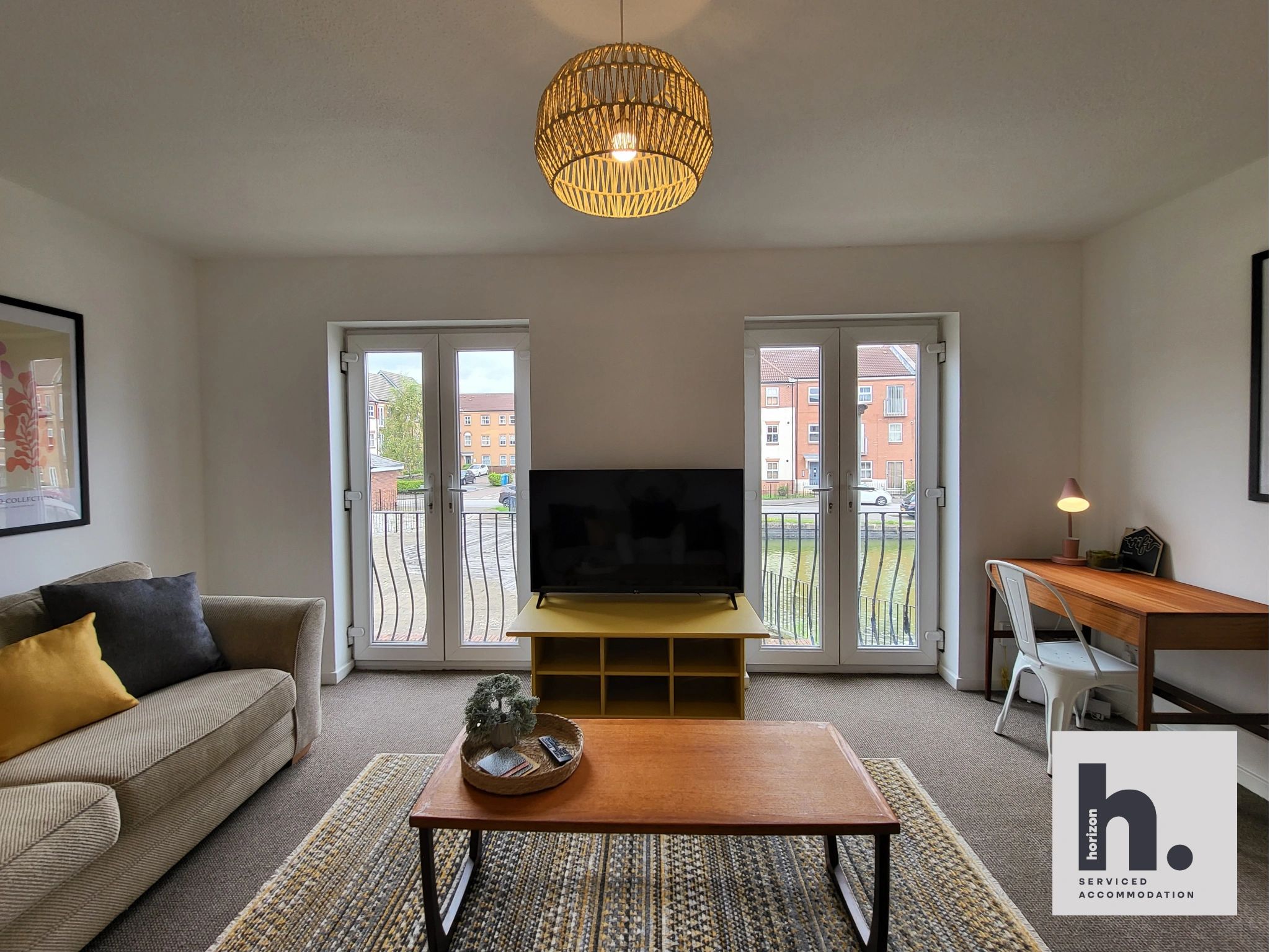 Cozy living room with a TV, sofa, and desk by the windows.