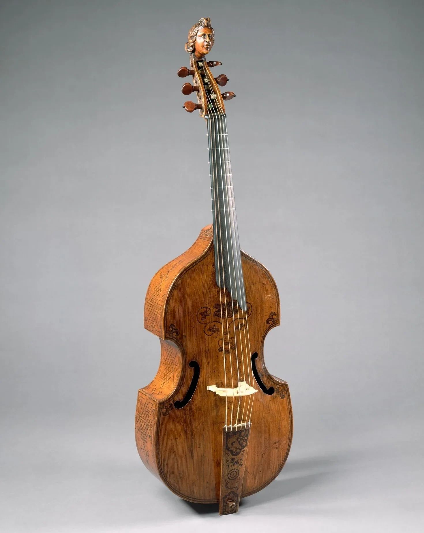 An antique string instrument with a carved human head at the top.