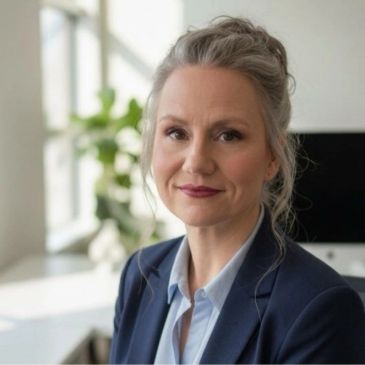 Professional woman in business attire smiling softly in a modern office.
