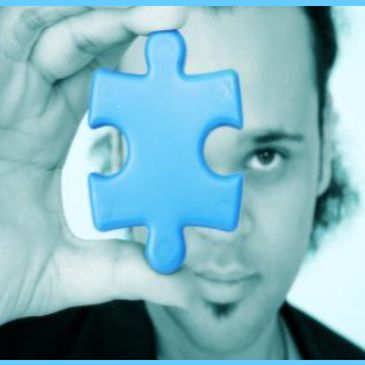 Man holding a puzzle piece in front of his face.