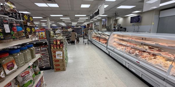 Supermarket aisle with deli meats and packaged goods.