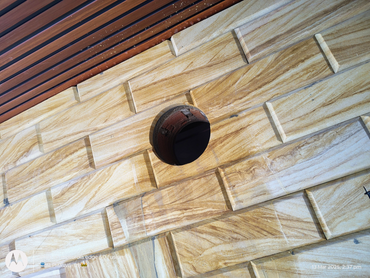 A round pipe opening on a textured stone wall with brown and beige tones.