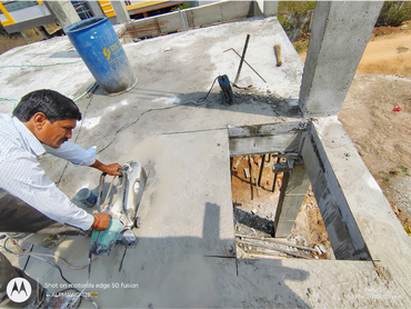 Man cutting concrete slab with a power saw at a construction site.