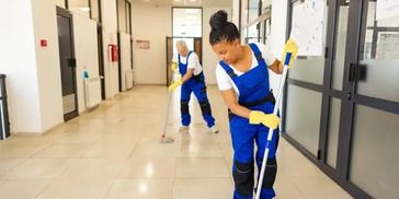 Two commercial cleaners mopping medical office hallway