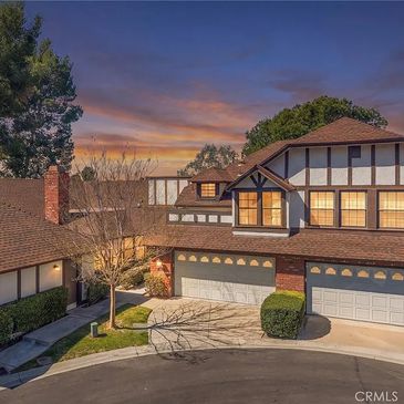 Two-story suburban house at sunset with garage and driveway.