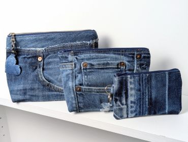 Three denim bags of different sizes on a shelf.