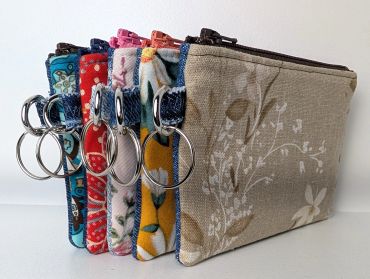 A row of floral fabric pouches with keyrings.