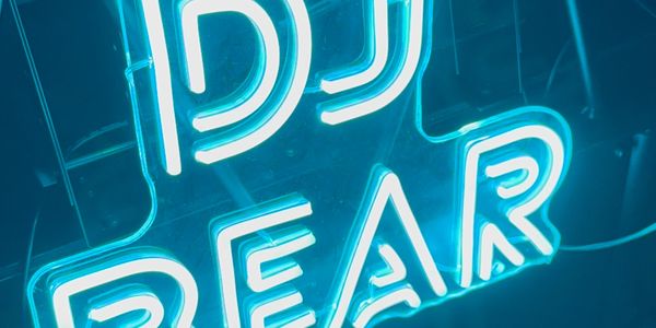 Bright blue neon sign reading 'DJ BEAR' glowing in the dark.