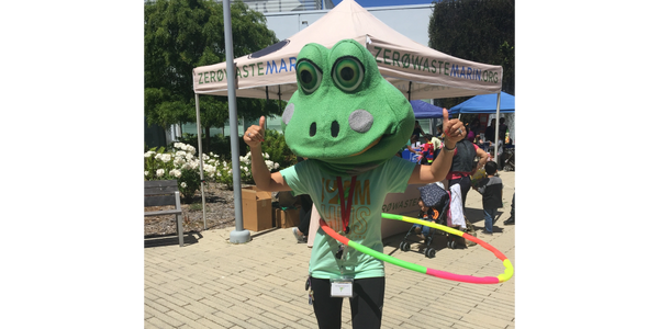 Someone wearing a giant frog head while hula hooping