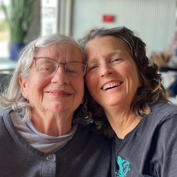Two women smiling closely together in a warm, loving embrace.