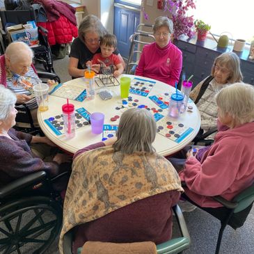 Elderly people and a child play bingo together around a table.
