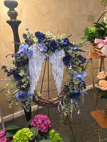 Floral wreath with angel wings on display in a cozy room.