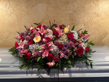 Elegant floral arrangement with roses and lilies on a casket.
