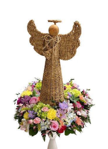 Woven angel decoration surrounded by colorful flowers.