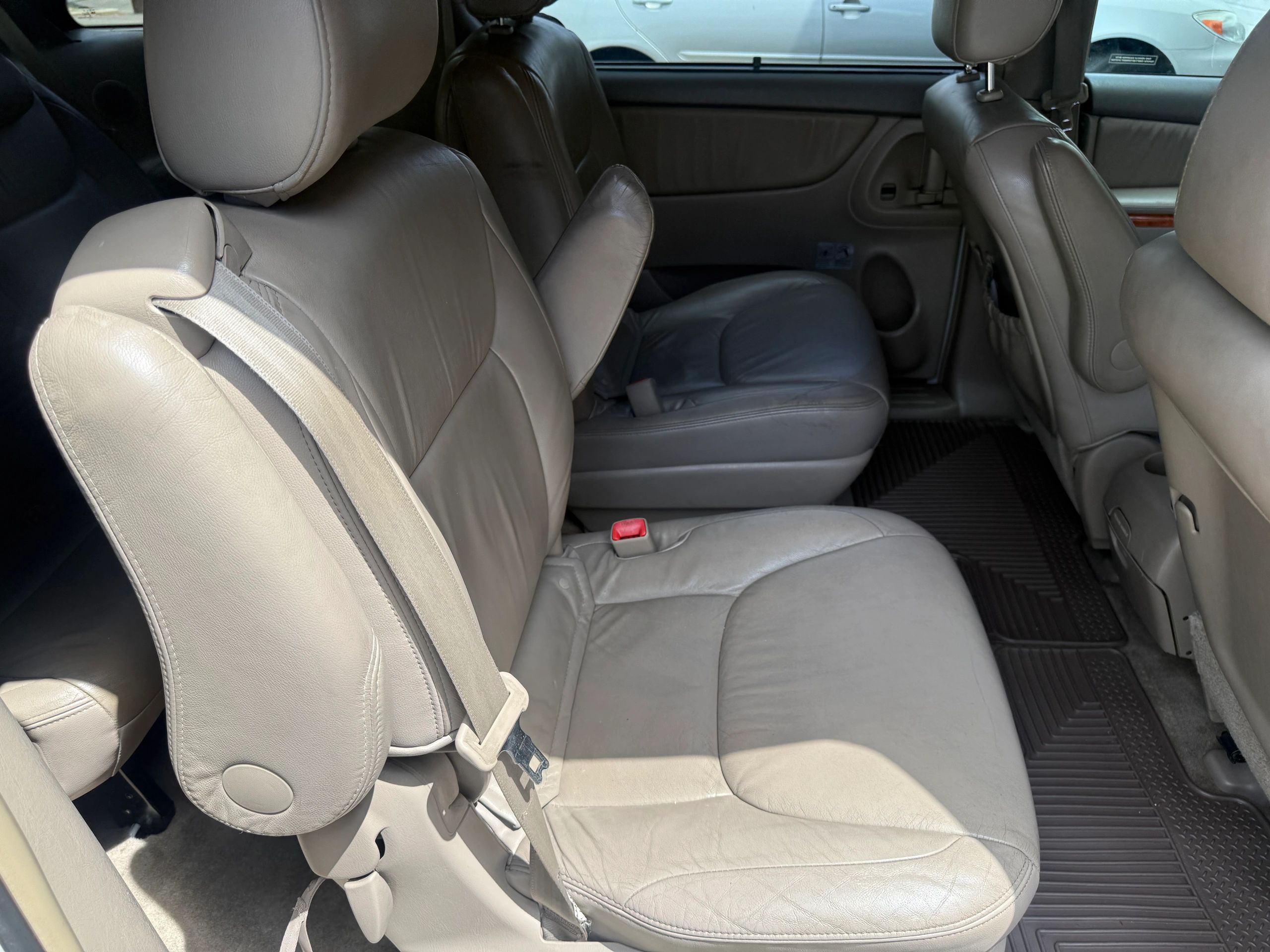 Beige leather car seats with a foldable armrest in a spacious interior.